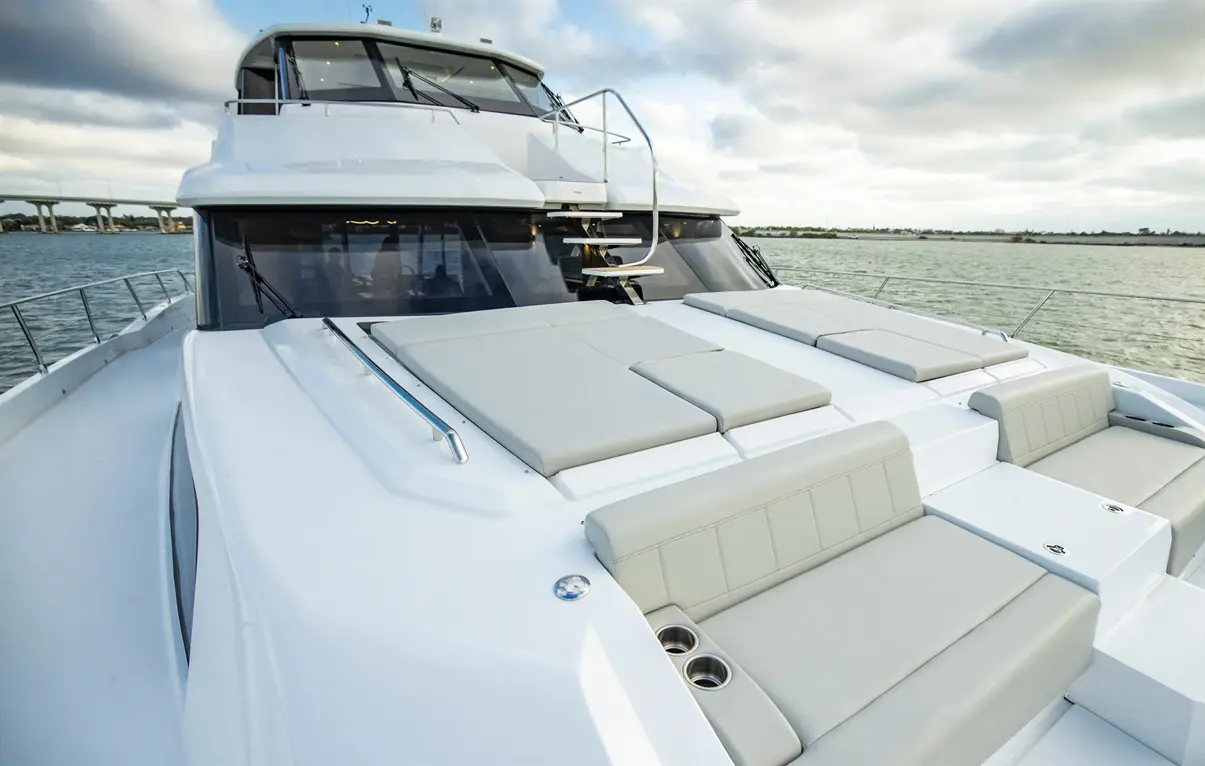 Luxury yacht deck with grey padding, a handrail, and panoramic views of water and cloudy skies in the background.